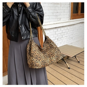 Detailed view of leopard print tote bag with golden chain straps worn by a model