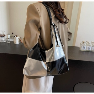 Close-up of a silver and black patchwork hobo bag with glossy finish and drawstring detail