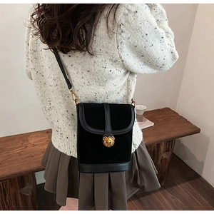 Close-up of vintage black matte suede crossbody bag with golden bear metal clasp