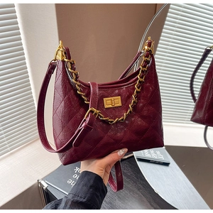 Dettaglio macro della borsa in pelle trapuntata bordeaux con catena d'oro e chiusura