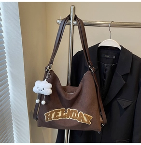 Détail du sac cabas marron foncé avec broderie HELNDAY et breloque peluche nuage blanc
