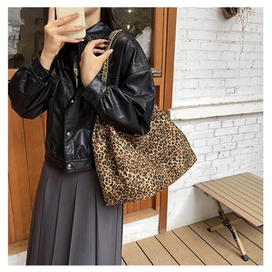 Detail of leopard print tote bag with thick gold chain strap worn by a model