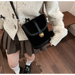 Detail showing vintage black bucket bag with golden bear buckle worn on a model
