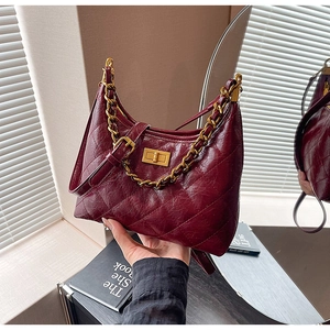 Dettaglio borsa in pelle trapuntata bordeaux con catena dorata e chiusura a girello