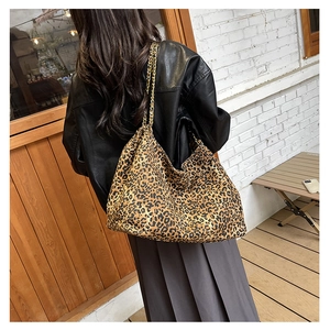 Detail of leopard print tote bag with dual gold chain straps and canvas texture