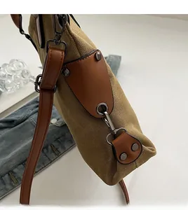 Détail d'un sac cabas en toile avec garniture en cuir brun et mousqueton en métal vieilli