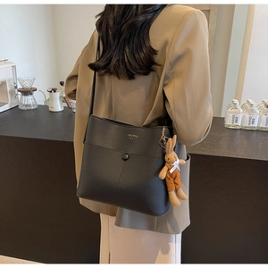 Detail of black bucket bag with lychee texture and cute rabbit plush charm accessory