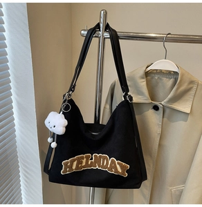 Détail d'un sac fourre-tout en toile noire avec patch FIELDAY marron et pendentif