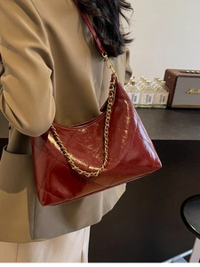 Sac matelassé bordeaux avec chaîne dorée porté par un mannequin dans un style rétro