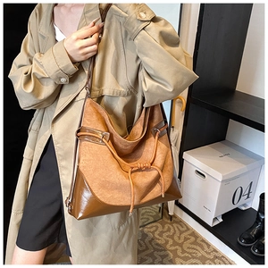 Detail view of large brown suede shoulder bag with leather drawstring and patchwork finish