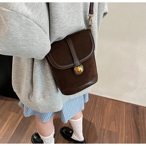 Detail of vintage brown bucket bag featuring contrast leather trim and a golden bear clasp
