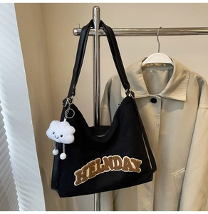 Détail du sac Hobo en toile noire avec lettrage MELNDAY et charm nuage en peluche