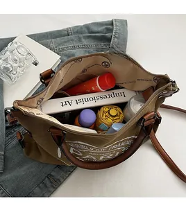 Intérieur spacieux du sac cabas en toile olive contenant parapluie, livres et accessoires