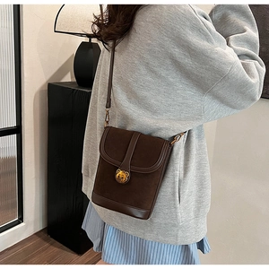 Detail of vintage brown bucket bag featuring a gold bear clasp and suede texture