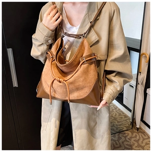 Detail of suede bucket bag with contrast leather trim and drawstring on model