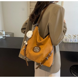 Détail du sac hobo en daim moutarde avec logo M et breloque nuage en peluche blanche