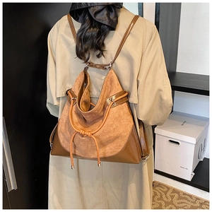 Brown suede backpack with leather panels shown from a back view on a model