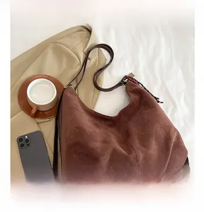 Detail of a brown suede hobo bag with adjustable strap and decorative floral silk scarf