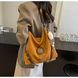 Détail du sac cabas gingembre avec logo M métallique et pompon blanc en peluche