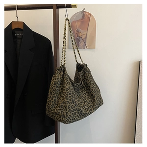 Detail of leopard print tote bag featuring gold chain strap and textured fabric
