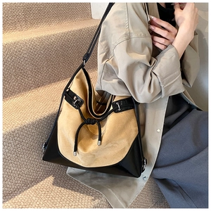 Detail of beige suede and black leather tote bag with decorative knot on a model