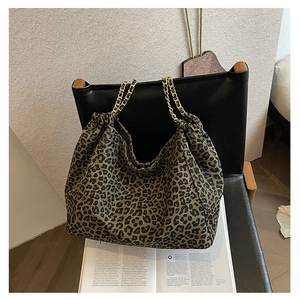 Detail of leopard print tote bag with gold chain strap and drawstring closure on chair