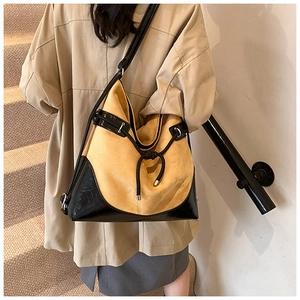 Detail of suede and leather crossbody bag with adjustable strap on a female model