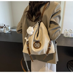 Détail du sac cabas beige avec logo M, bordure en cuir marron et breloque nuage blanc