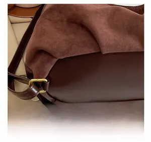Detail view of dark brown tote bag showing mixed textures and gold hardware buckle