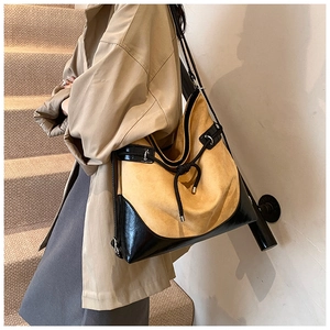 Detailed close-up of large suede shoulder bag with patchwork leather and drawstring