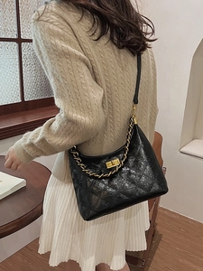 Borsa a spalla trapuntata nera con catena dorata indossata da una modella donna