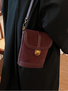 Vintage burgundy bucket bag with golden bear clasp shown on model's shoulder