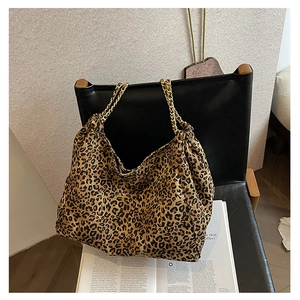 Detail of leopard print tote bag with golden metal chain straps on a leather seat
