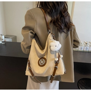 Dettaglio della borsa tote beige con tracolla in pelle e ciondolo a nuvola sulla spalla