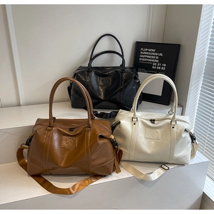 Detailed view of large travel bags in brown, black, and beige PU leather with shoulder straps