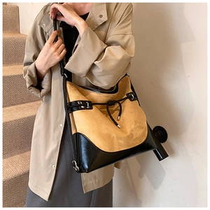 Detail of suede tote bag with contrast black leather trim and decorative knot detail