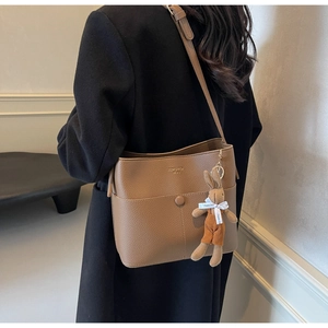 Detailed texture of brown pebble leather bucket bag with a cute plush bunny charm