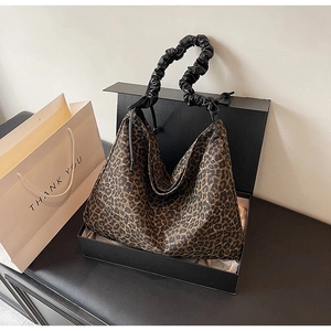 Detailansicht der Handtasche mit Leopardenmuster und gerafftem Griff in einer Geschenkbox