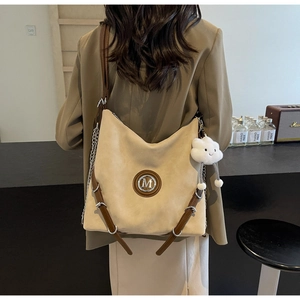 Détail du sac fourre-tout beige en daim avec lanières en cuir marron et breloque nuage