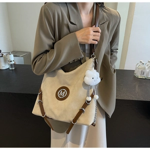Détail du grand sac cabas avec logo M, lanières en cuir marron et breloque nuage