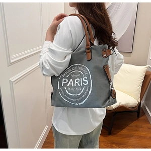 Vue latérale d'un grand cabas en toile grise avec anses en cuir marron et imprimé Paris