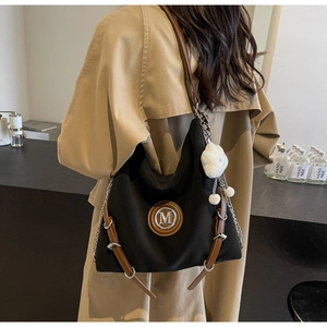 Détail du sac cabas noir avec logo M argenté, garniture cuir et bijou de sac nuage