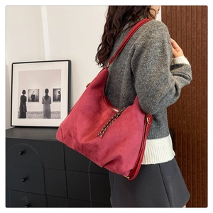 Detail of red suede tote bag showing large capacity and decorative woven zipper pull