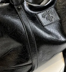 Close-up of black vintage wrinkled leather bag texture with metal rivet details