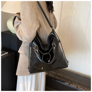 Close-up of black high-shine oversized tote bag with drawstring detail and metal hardware
