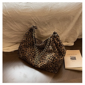 Macro shot of stylish leopard print tote bag with golden chain straps on wooden floor