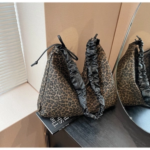 Detail der Tragetasche mit Leopardenmuster und schwarzem gefaltetem Ledergriff am Tisch