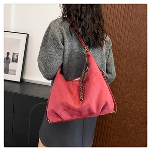 Close-up of red matte suede tote bag with golden hardware and woven tassel detail