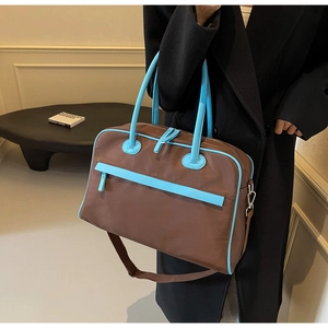 Makro-Detail einer großen braunen Reisetasche mit blauen Griffen und Schultergurt