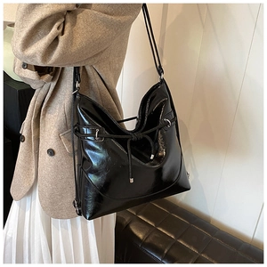 Side view of large black patent leather tote with drawstring detail and glossy finish